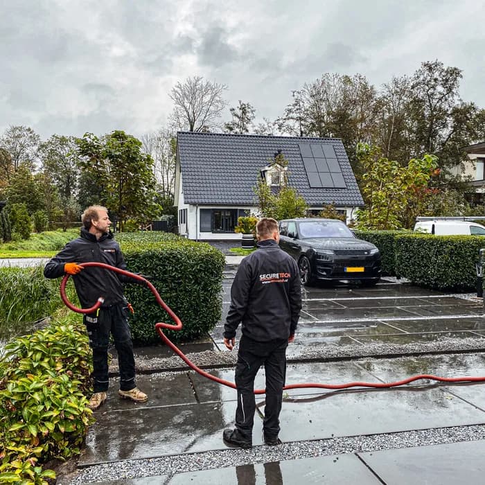 Securetech monteurs trekken kabels bij een woning tijdens een installatie